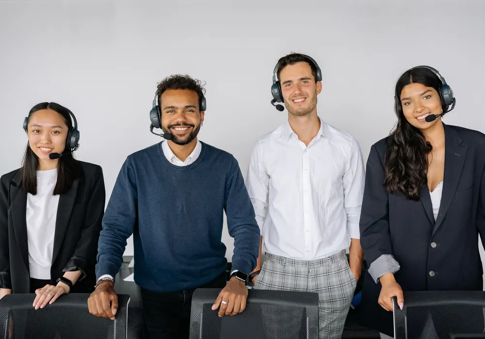 Smiling customer support team standing together wearing headsets