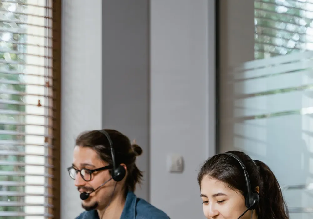 Support colleagues with headsets working on laptops in a bright office