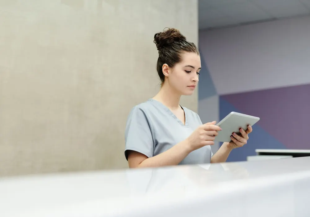 Medical receptionist using a tablet at a clinic front desk