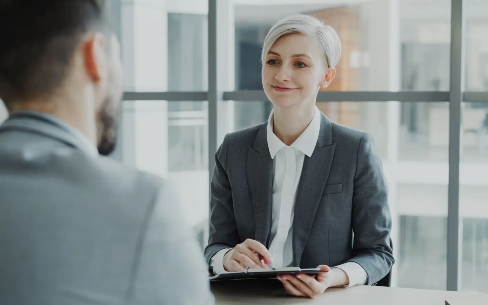 Recruiter interviewing a candidate in a modern office with large windows