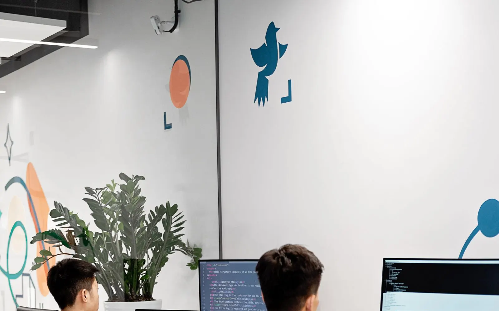 Two team members working at computers in a bright modern office