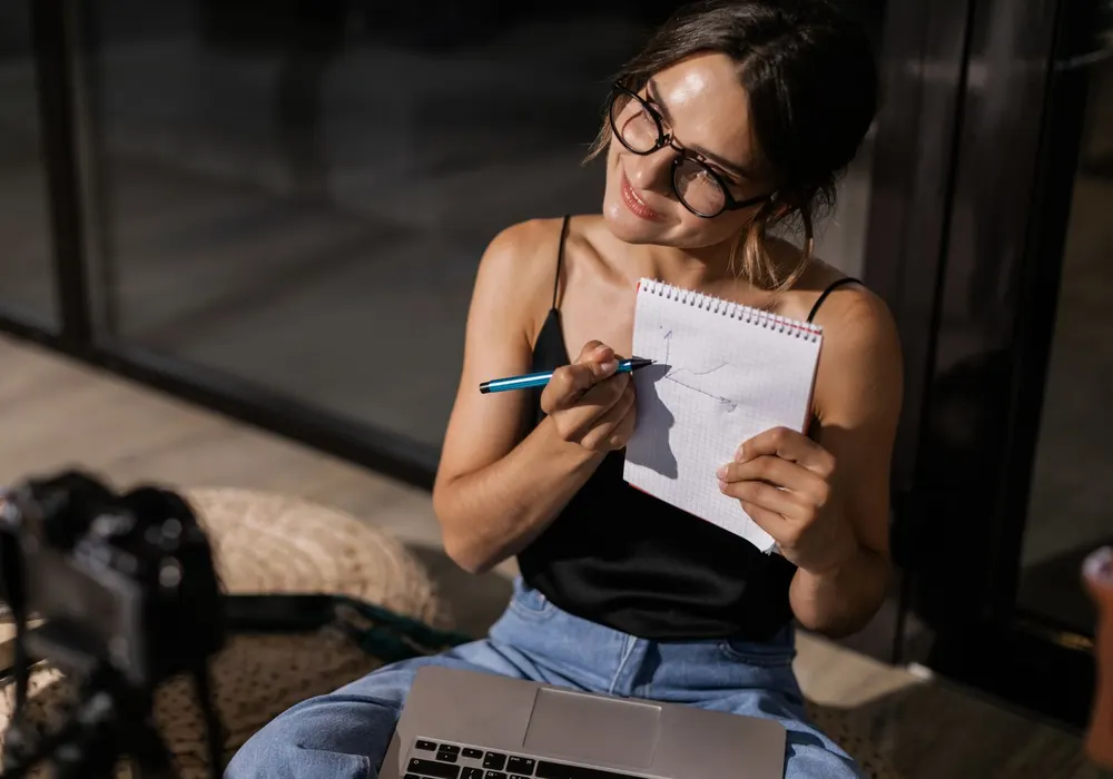 Content creator planning posts in a notebook beside a camera