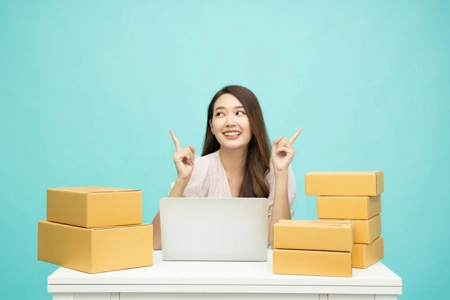 Smiling woman at a laptop with shipping boxes on her desk